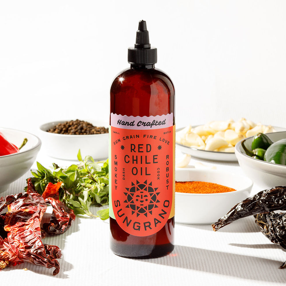 A 16oz bottle of Sungrano Red Chile Oil with dried chiles, garlic and herbs