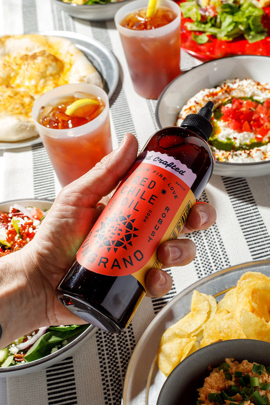 Friends sharing food with a bottle of Sungrano Red Chile Oil